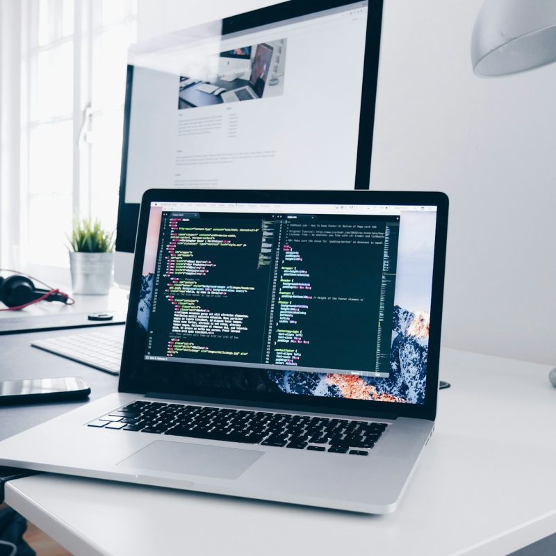 Un MacBook con líneas de código en su pantalla en un escritorio ocupado